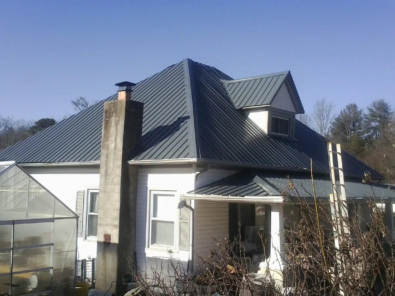 Dark blue standing seam metal roof on a white farmhouse with dormer — Slate & Tile Roof Repair by Roofing Brothers in Indiana