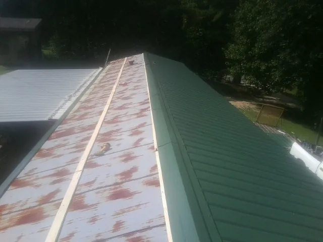 Old rusted panels beside newly installed green metal roofing — Wind Damage Roof Repair by Roofing Brothers in Indiana