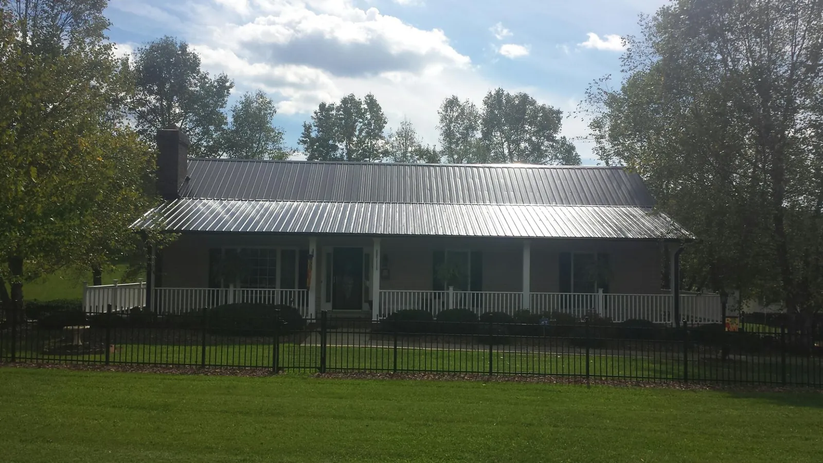 Gray metal roof on a brick ranch with a full width front porch — Gutter Guard Installation work by our crew in Indiana