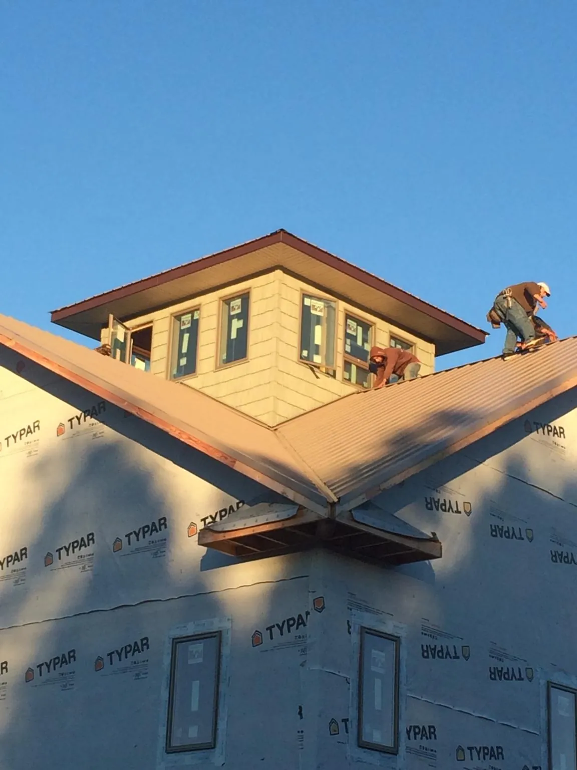 Roofers working around a rooftop cupola on a new metal roof at sunset — Roof Waterproofing in Indiana by Roofing Brothers